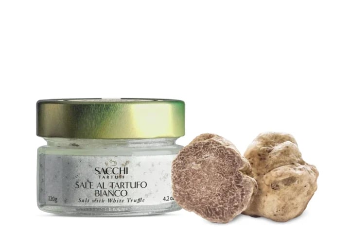 Jar of Sacchi white truffle salt with two fresh white truffles on a white background