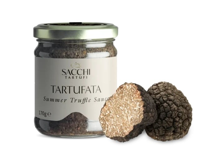 Sacchi Tartufi truffle sauce jar with fresh whole and sliced black truffles displayed beside it